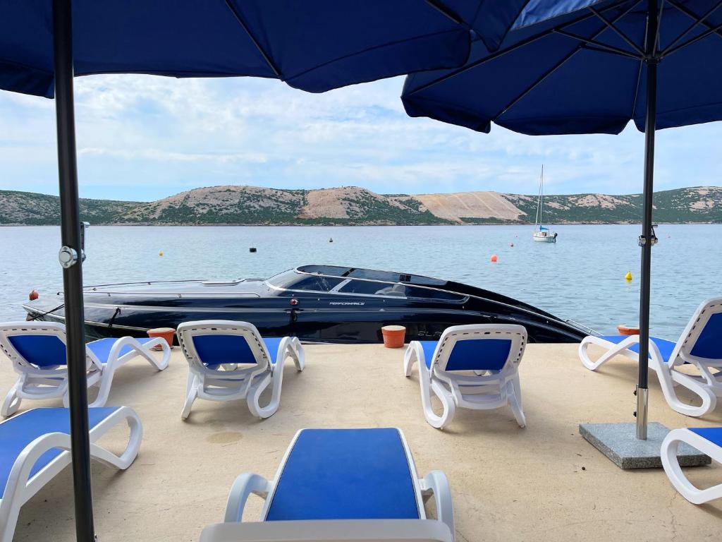 a group of chairs and umbrellas and a boat on the water at Villa Olivija-direkt am Strand! in Stara Novalja