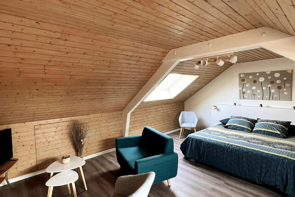 - une chambre avec un grand lit et une chaise bleue dans l'établissement Au Repos du Fayé, à Grosmagny