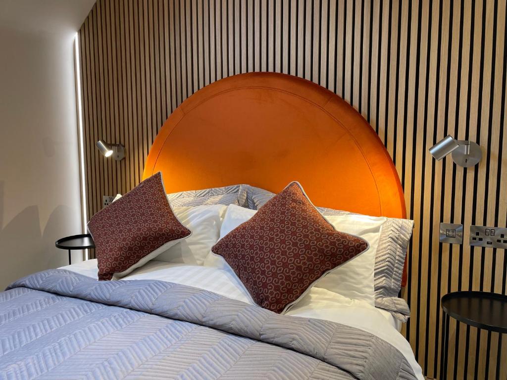 a bed with an orange headboard with pillows on it at The Boutique Hotel in Faringdon