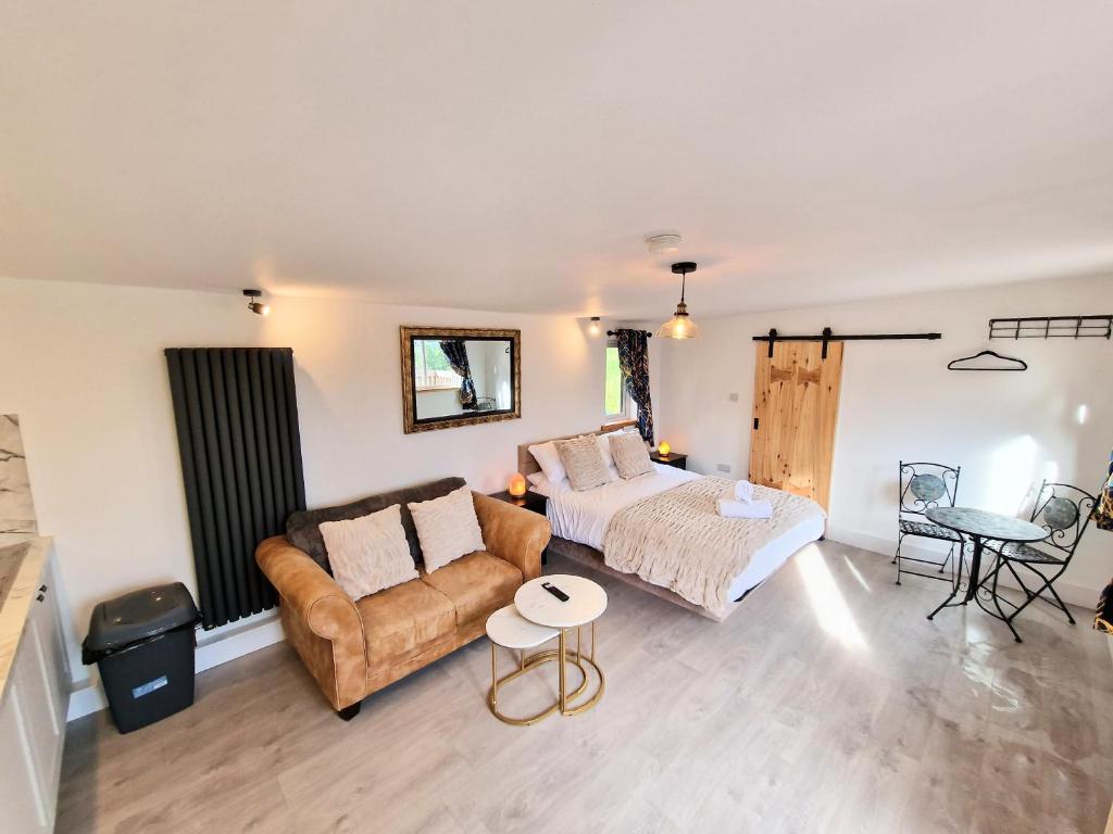 uma sala de estar com um sofá e uma cama em Kaoglen Lodge - Fawn Pod - Hot Tub - Dogs - Pitlochry - Luxury em Blairgowrie