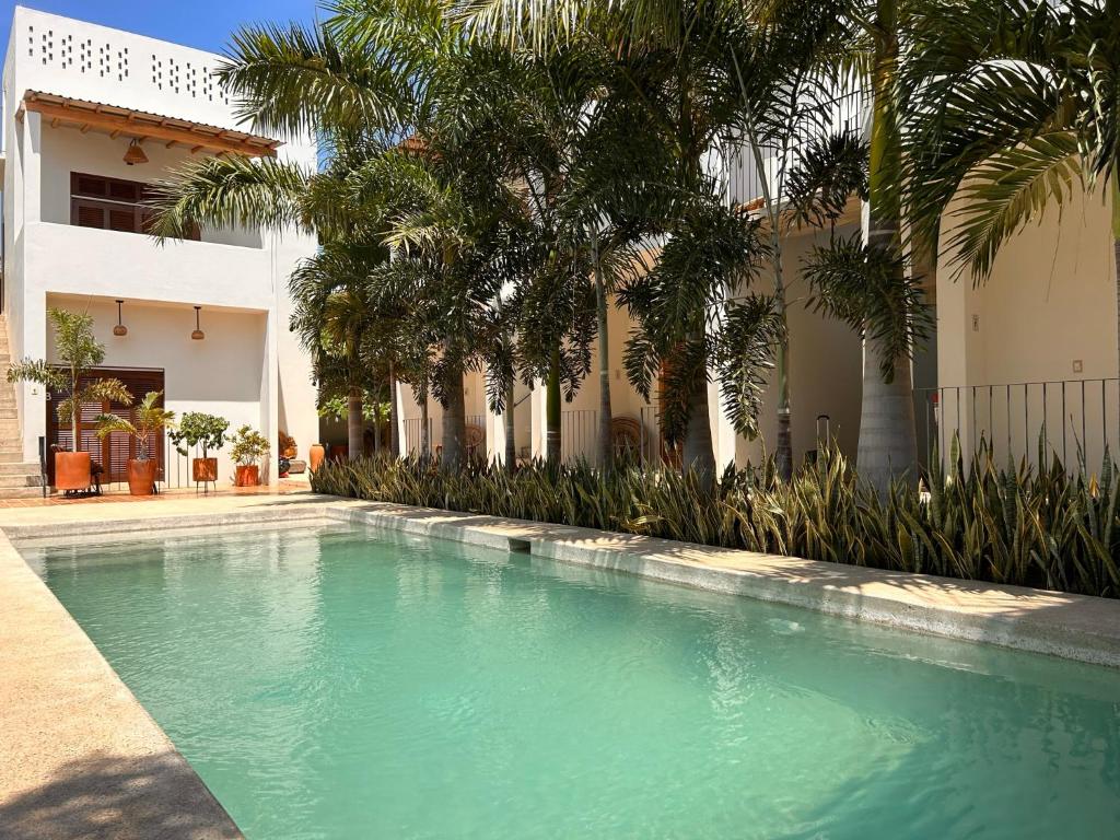 uma piscina em frente a uma casa com palmeiras em Hotelito Zicatela Cam a la Cruz 70938 Puerto Escondido Oax em Brisas de Zicatela