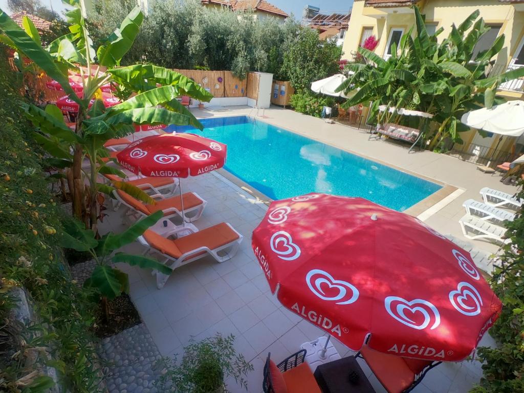a pool with two red umbrellas and chairs and a swimming pool at Sarıhan Apart Otel in Oludeniz