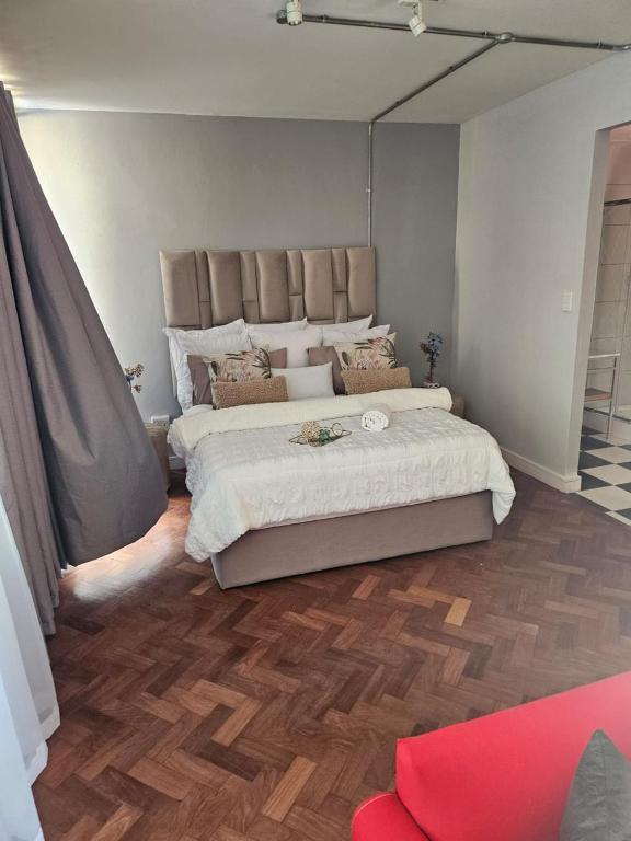 um quarto com uma cama grande e piso em madeira em @Derricks Luxury Apartments 2 em Joanesburgo