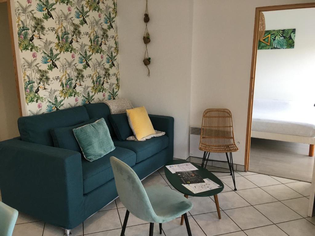 a living room with a blue couch and a table at La marine D&#39;opale in Ambleteuse