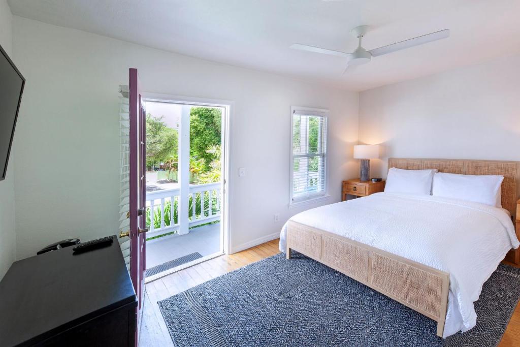 a white bedroom with a bed and a window at Coco Plum Inn in Key West