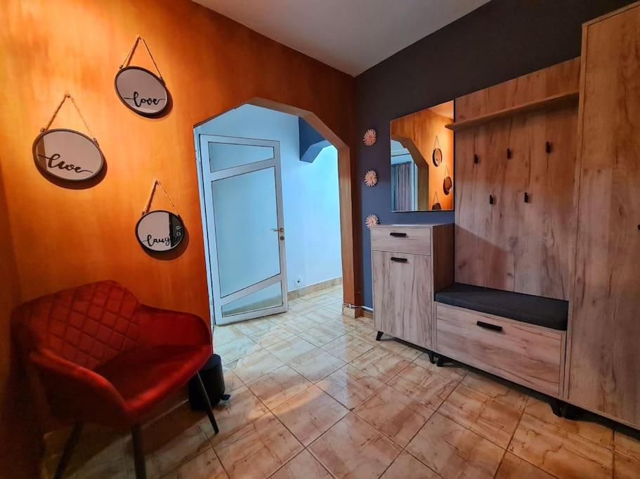 a bathroom with a red chair and a dresser and a mirror at Urban Nest Barlad in Bîrlad