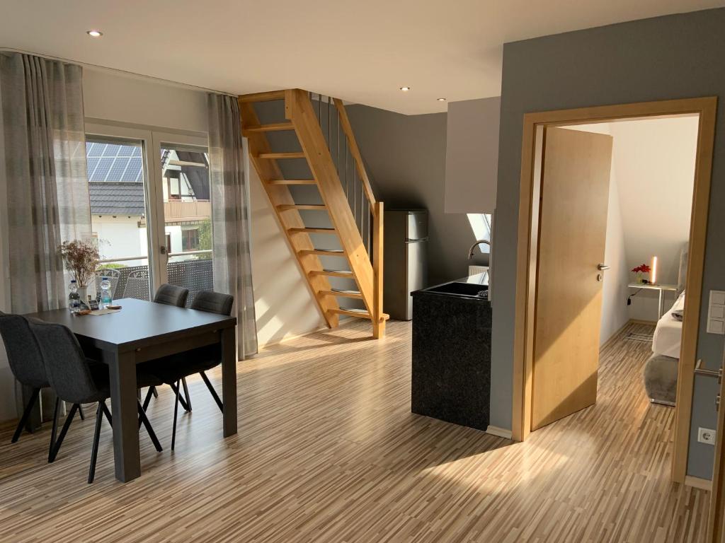 a living room with a dining room table and a staircase at BestBoarding24 in Schöllkrippen