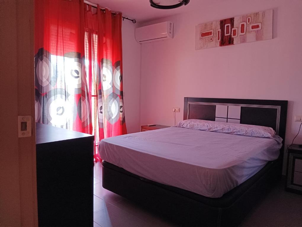 a bedroom with a bed and a window with red curtains at Cazorlasalud in Santo Tomé