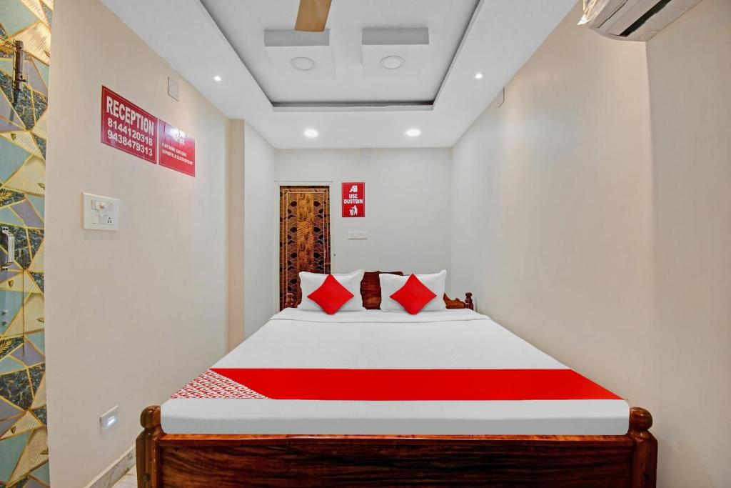 um quarto com uma cama com lençóis vermelhos e brancos em OYO Pratikshya A1 Residency em Bhubaneshwar