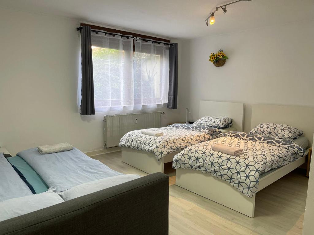 a room with three beds and a couch and a window at Düsseldorf Messe, 2-bedroom Duplex Apartment with Terrace and Garden in Düsseldorf