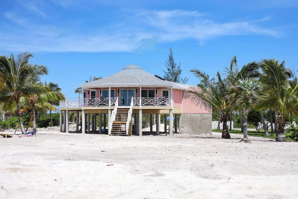 a pink house on the beach with palm trees at Leisure Beach Ocean Retreat in Lower Bogue