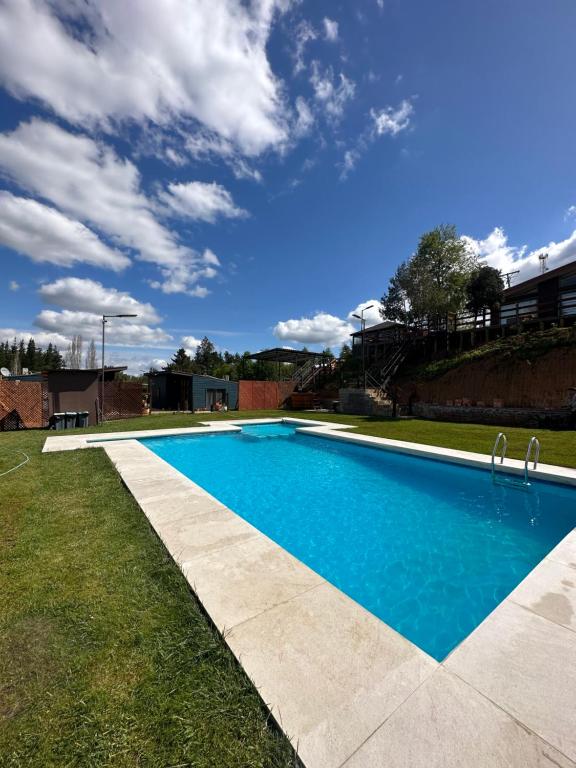 a swimming pool in a yard with a blue sky at Ecoraleo in Concepción