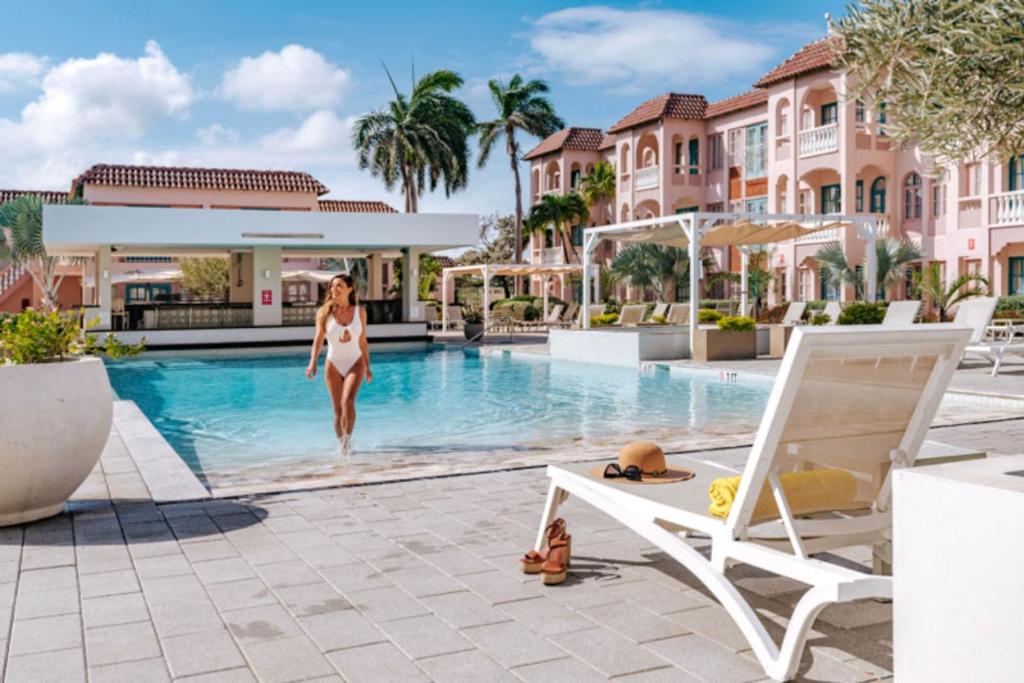 una mujer entrando en una piscina en un complejo en Caribbean Palm Village Resort, en Palm-Eagle Beach