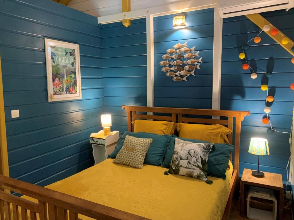 una camera da letto con pareti blu e un letto con cuscini di Un p'tit coin Zen a Saint-François