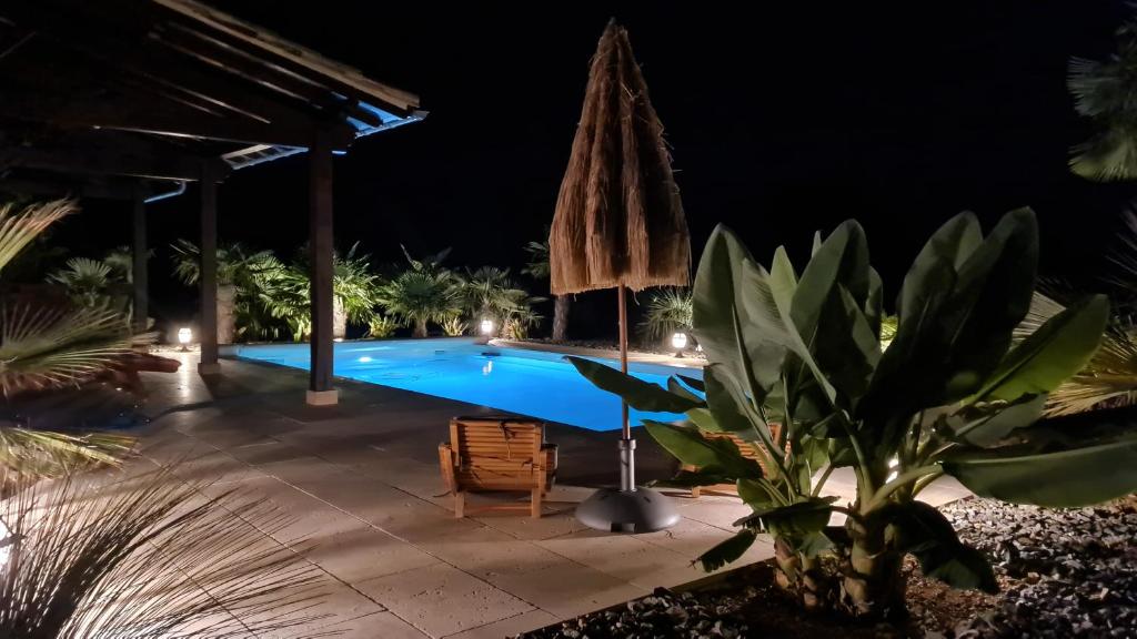 a swimming pool at night with a umbrella at Le Relais des Chevaliers "La Suite des Seigneurs" in Cordes-sur-Ciel