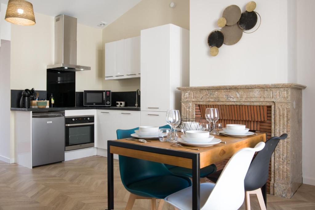 uma cozinha com uma mesa de madeira com cadeiras e uma sala de jantar em Appartement T2 de haut standing classé trois étoiles, hypercentre Rochefort, arrivée autonome em Rochefort
