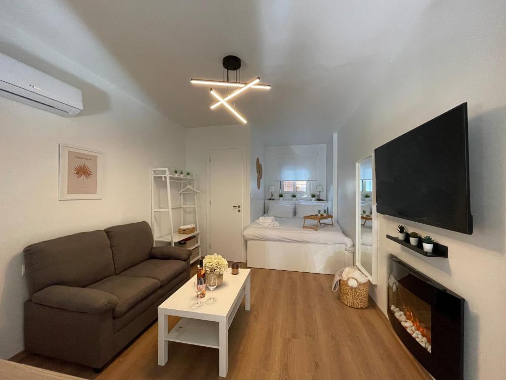een woonkamer met een bank, een tv en een bed bij Persephone Stay Inn in Elefsina