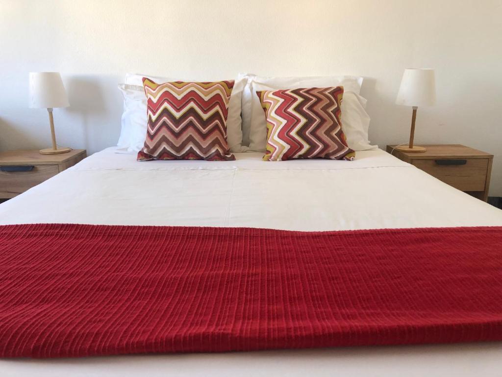 a large bed with a red blanket on it at Santiago Guesthouse in Aveiro