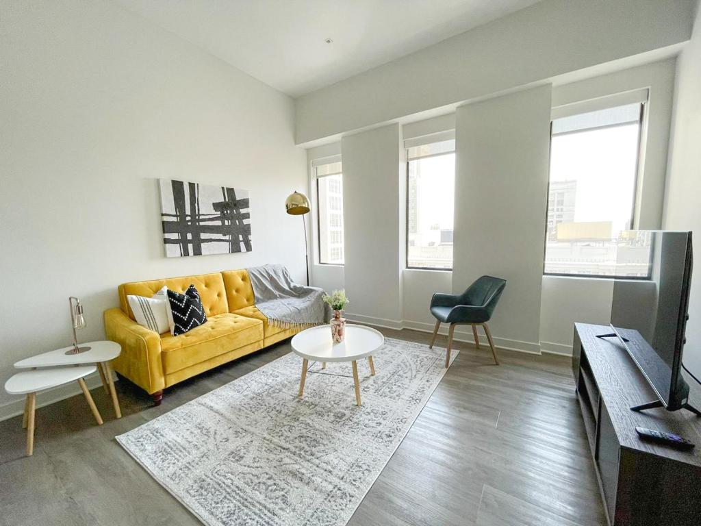 sala de estar con sofá amarillo y mesa en Sleepover Exclusive 1BD 1BA Downtown Kansas City Apartments, en Kansas City
