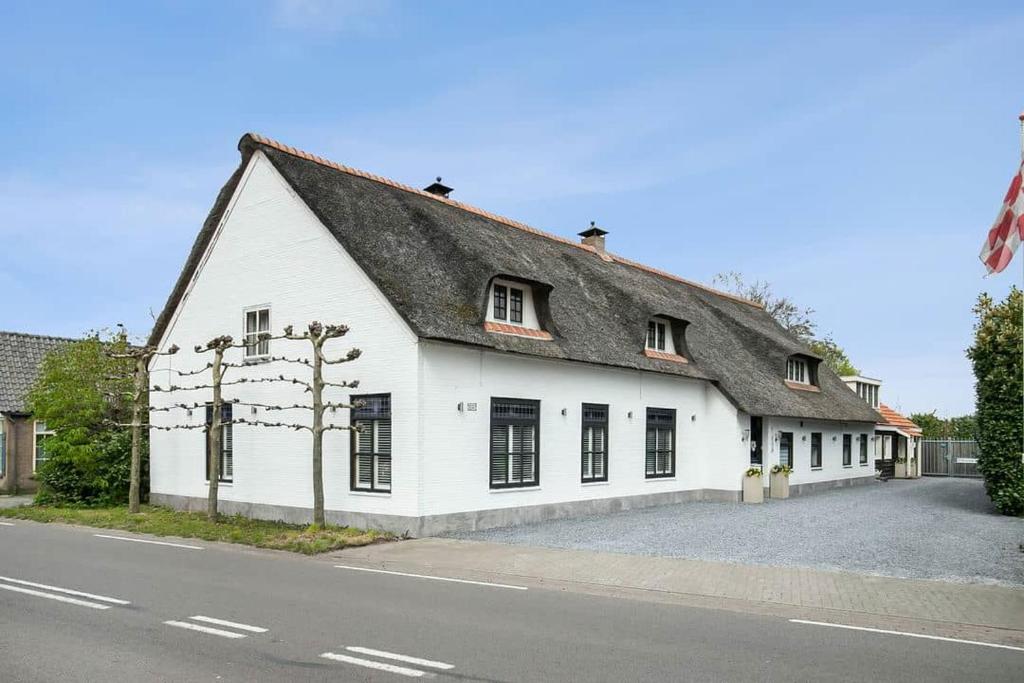 un bâtiment blanc avec un toit noir dans une rue dans l'établissement Guesthouse MAX, à Dongen