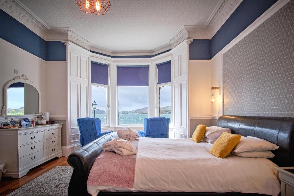 a bedroom with a large bed with blue walls and windows at MacKays in Oban