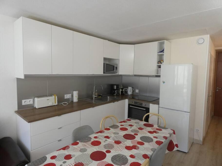 uma cozinha com uma mesa e uma cozinha com armários brancos em Appart 4/6 pers La Mongie em Bagnères-de-Bigorre