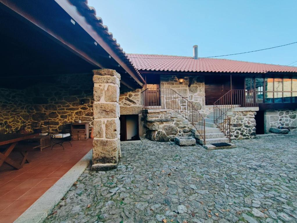 a stone house with a patio and a building at Casa das Falagueiras in Castro Laboreiro
