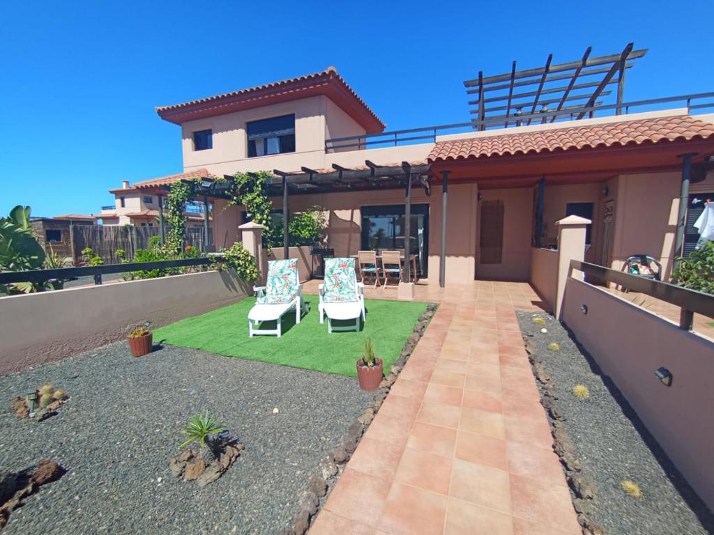 a house with a yard with two lawn chairs at Villardilla Fuerteventura in La Oliva