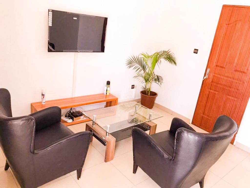 a living room with chairs and a table and a tv at Résidences KZOTOOL Ouaga in Ouagadougou