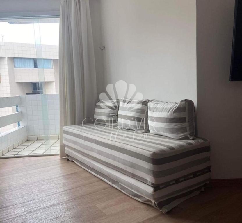 1 cama con almohadas a rayas en una habitación con ventana en Apartamento Cotê D'Azur à beira-mar., en Maceió