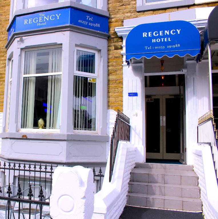 a white house with blue signs on the front of it at The Regency Hotel in Blackpool
