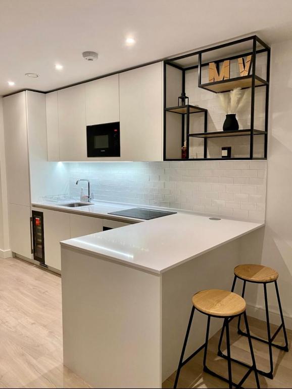 a kitchen with a white counter and two stools at 2 bed 2 bath luxury apartment in London
