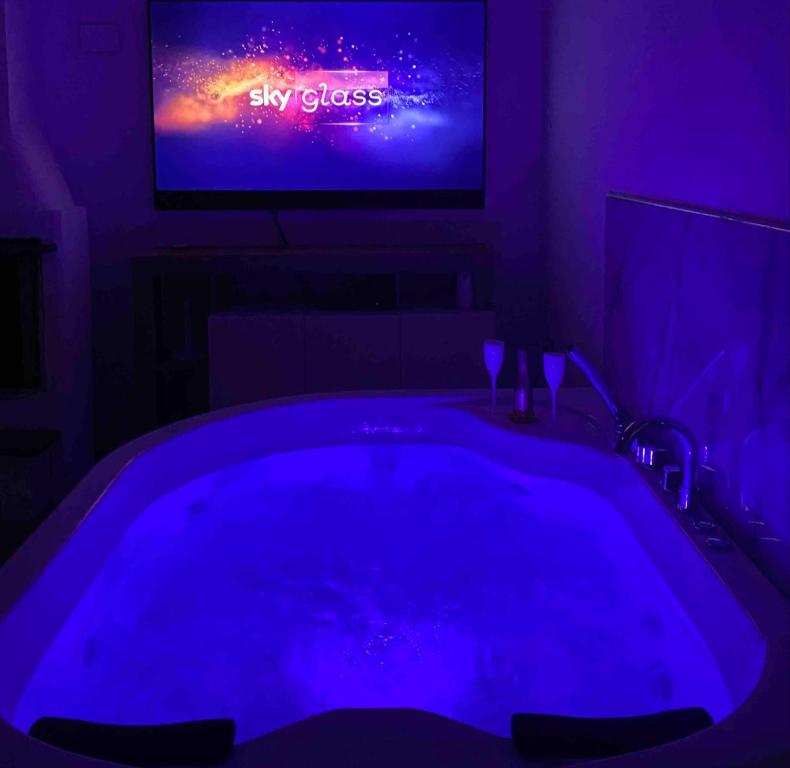 een donkere kamer met een groot bad en een tv bij Casa vacanza “oasi” in Salerno