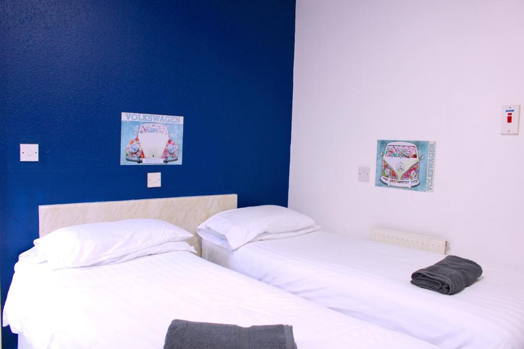 two beds in a room with a blue wall at The Regency Hotel in Blackpool