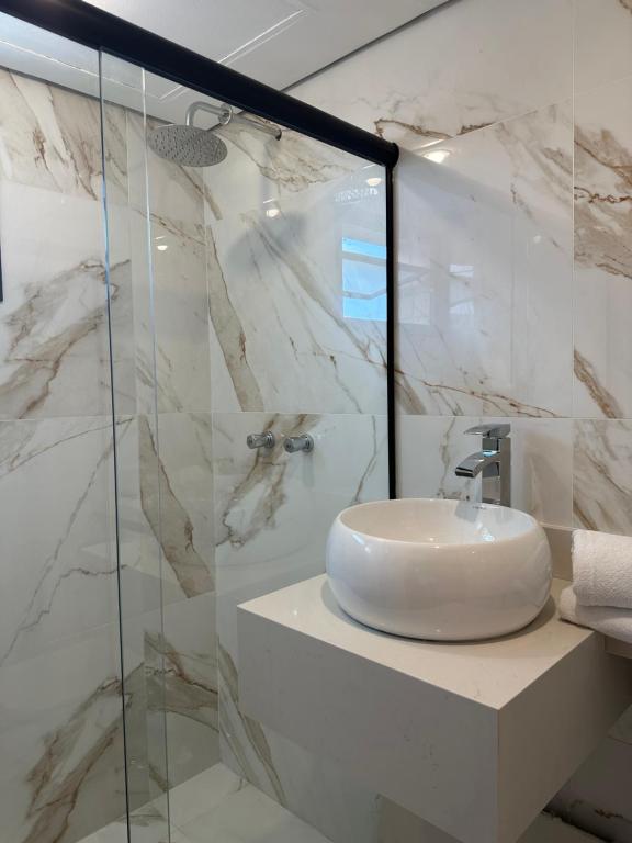 een badkamer met een wastafel en een glazen douche bij Hotel & Residência Alphaville in Barueri
