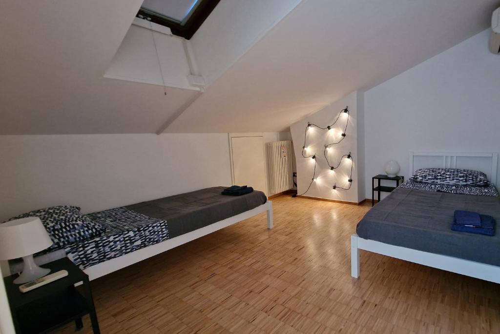 sypialnia z 2 łóżkami i lampką na ścianie w obiekcie la casa della luce w Weronie