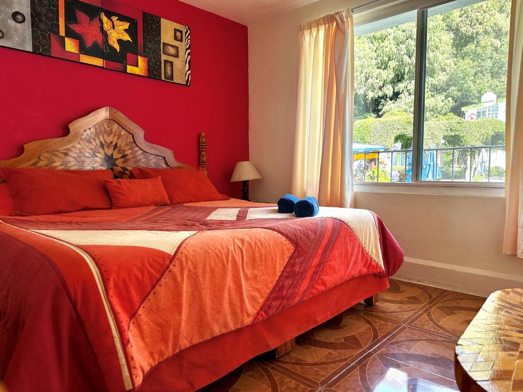 a bedroom with a bed with red walls and a window at BUNGALOWS ANDREA in Tepoztlán