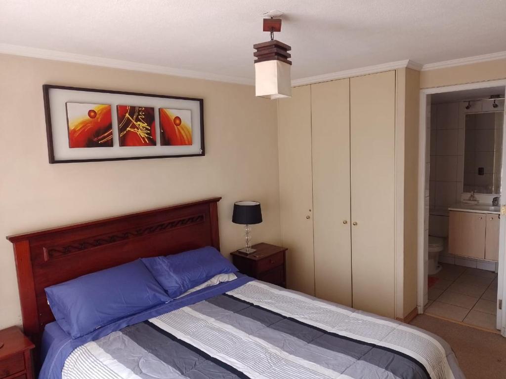 ein Schlafzimmer mit einem Bett und einem Bild an der Wand in der Unterkunft Santiago Apartotel Florida in Santiago