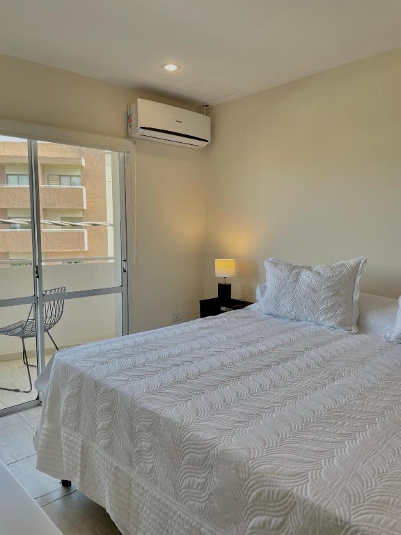 a white bed in a bedroom with a balcony at Complejo Hermogenes in San Juan