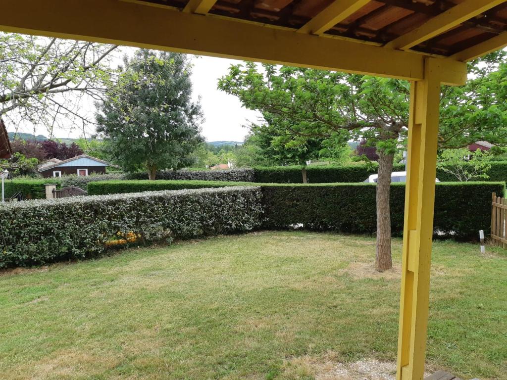 a yellow pergola in a yard with a hedge at Grand chalet en bois climatisé avec vue sur le lac in Saramon