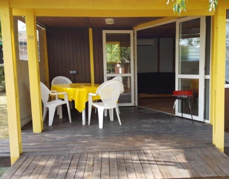 a yellow table and chairs on the porch of a house at Grand chalet en bois climatisé avec vue sur le lac in Saramon
