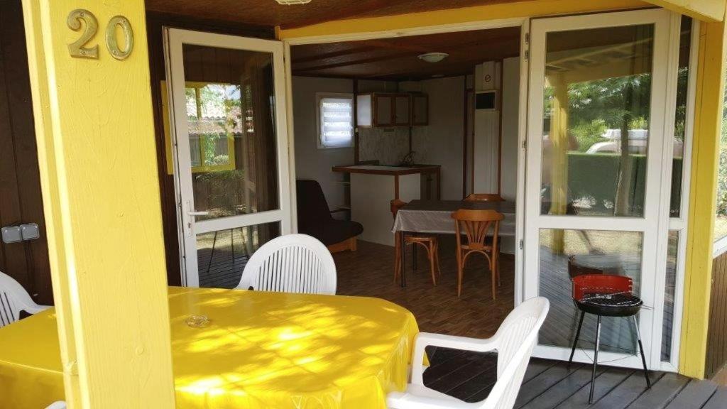 a yellow table and white chairs on a porch at Grand chalet en bois climatisé avec vue sur le lac in Saramon