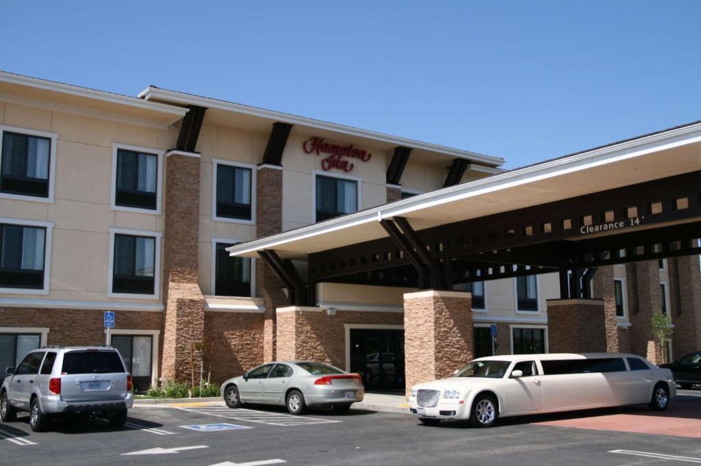 dos coches estacionados en un estacionamiento frente a un hotel en Hampton by Hilton, en Brentwood