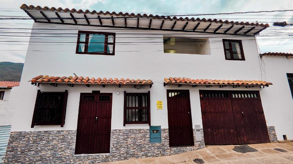 een wit huis met bruine deuren en ramen bij APARTAHOTEL CASA DE ANGEl 4 in Villa de Leyva