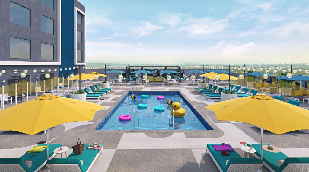 a pool with chairs and umbrellas on top of a building at Hilton Buena Park in Buena Park