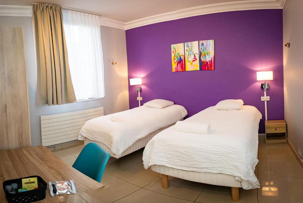 a room with two beds and a purple wall at Résidence Hélios Paris Orly Aéroport in Villeneuve-Saint-Georges