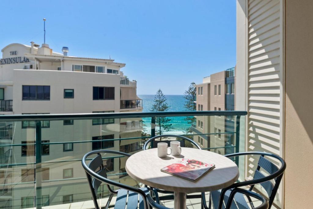 a table and chairs on a balcony with a view at Top Floor Beachside Apartment in the Heart of Mooloolaba in Mooloolaba