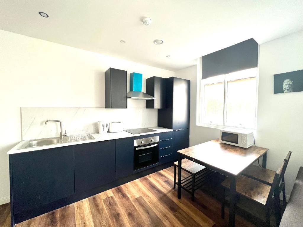 伍爾弗漢普頓的住宿－Apartment - City Centre WV1，厨房配有蓝色橱柜、桌子和水槽