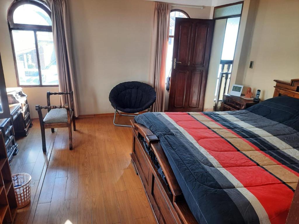 a bedroom with a bed and a chair and windows at Recidencia El Hogar in Cochabamba