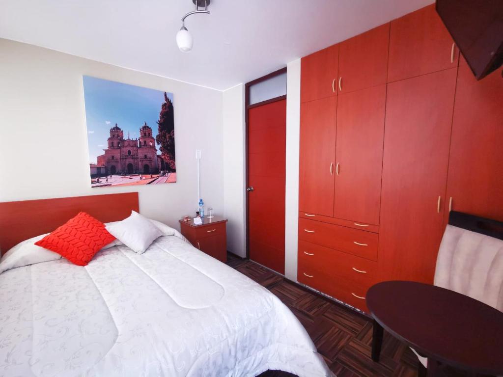 1 dormitorio con 1 cama con armarios rojos y mesa en Bon Repos Arequipa, en Arequipa